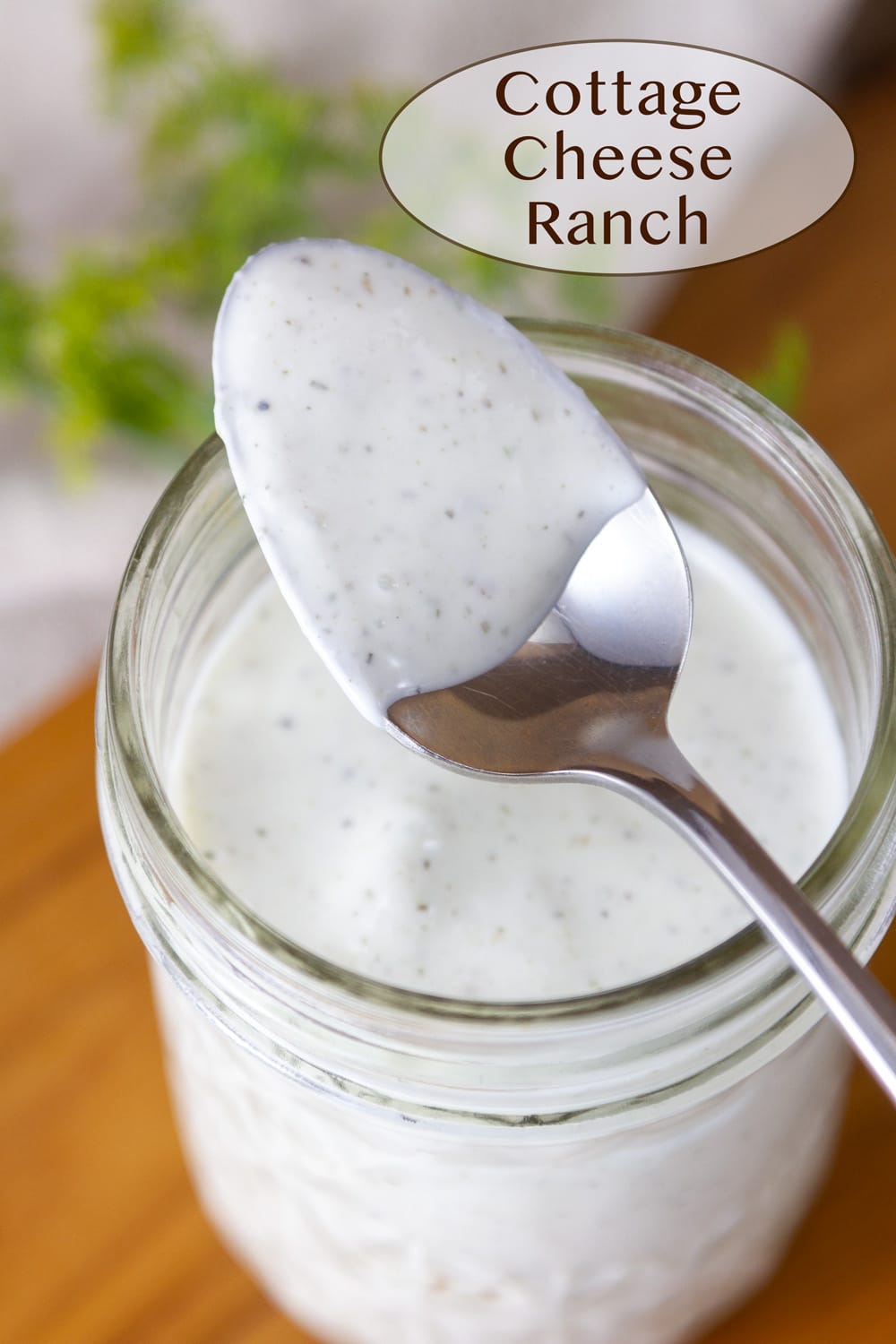 a mason jar filled with ranch dressing and a spoon on top that's been dipped in the dressing.