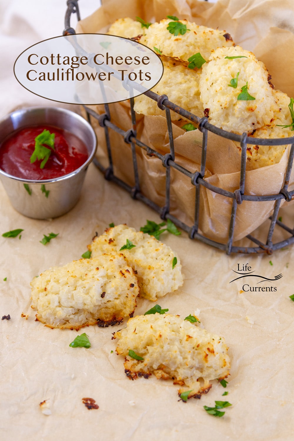 Three Cottage Cheese Cauliflower Tots on a piece of parchment paper next to dipping sauce and a basket of the tots.