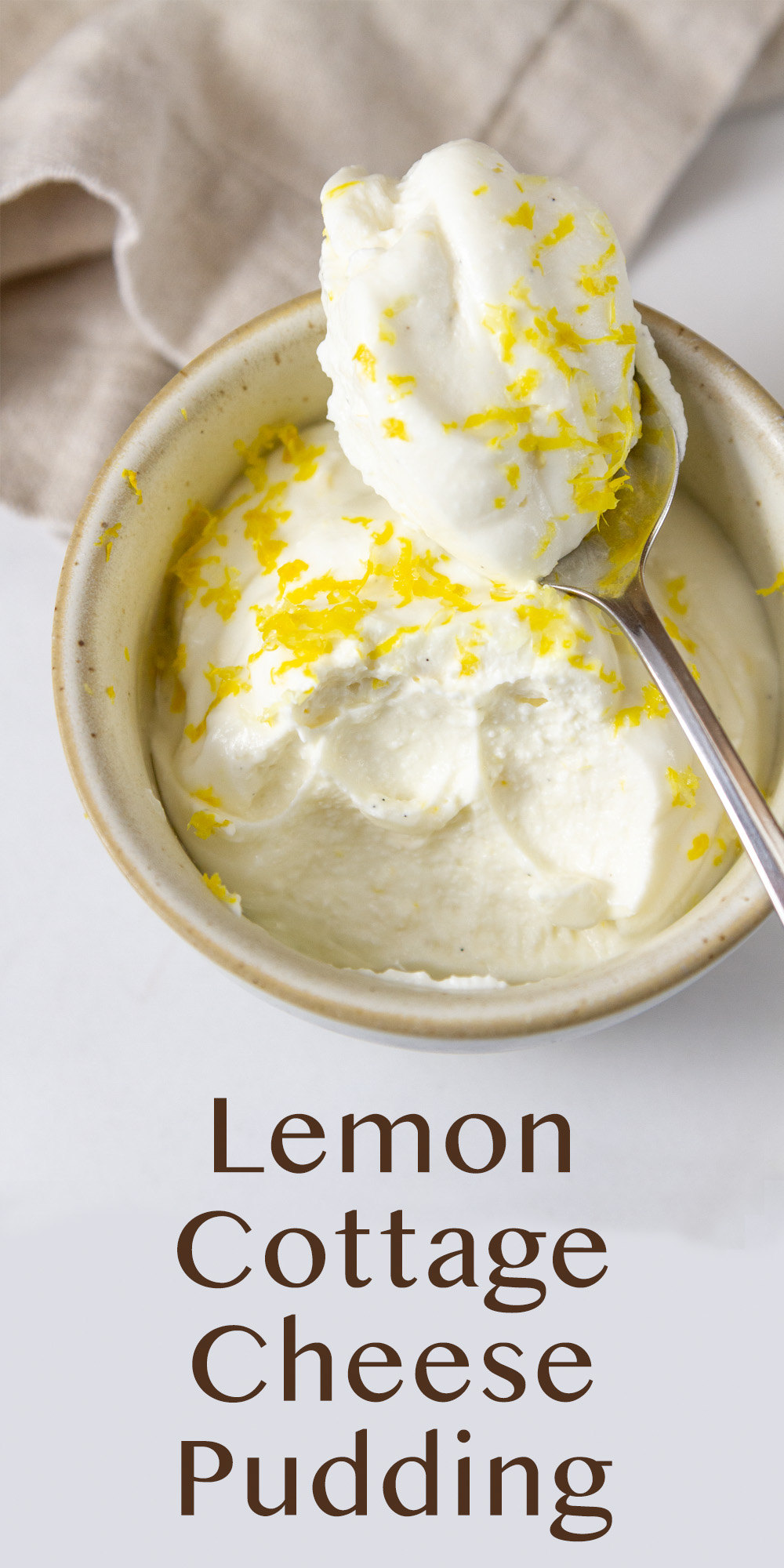 a dish of pudding that's topped with lemon zest and a spoon has taken a spoonful out and is sitting on the edge of the dish.